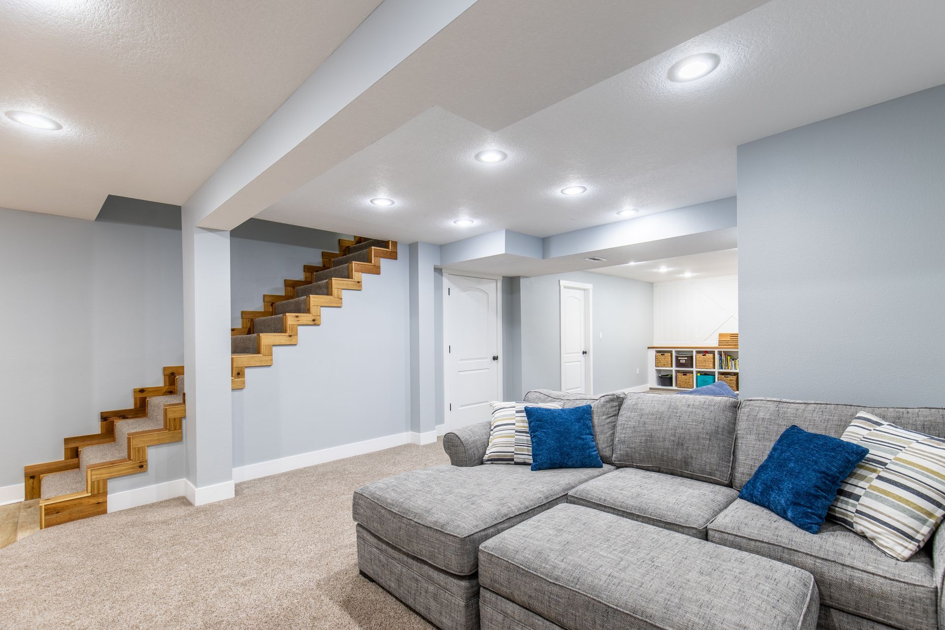 A living room in a basement with a couch and stairs.