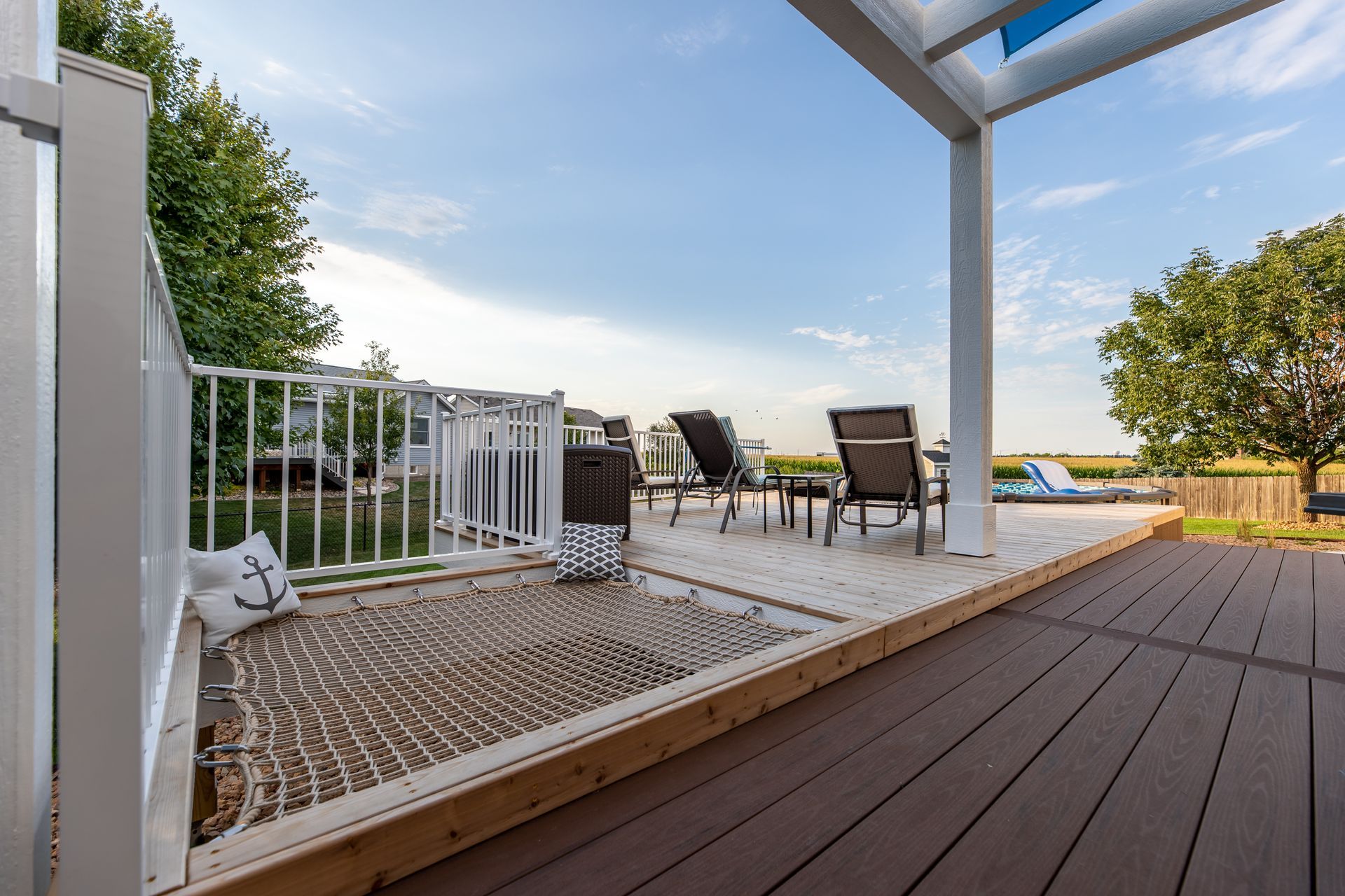 A deck with a hammock and chairs under a canopy.