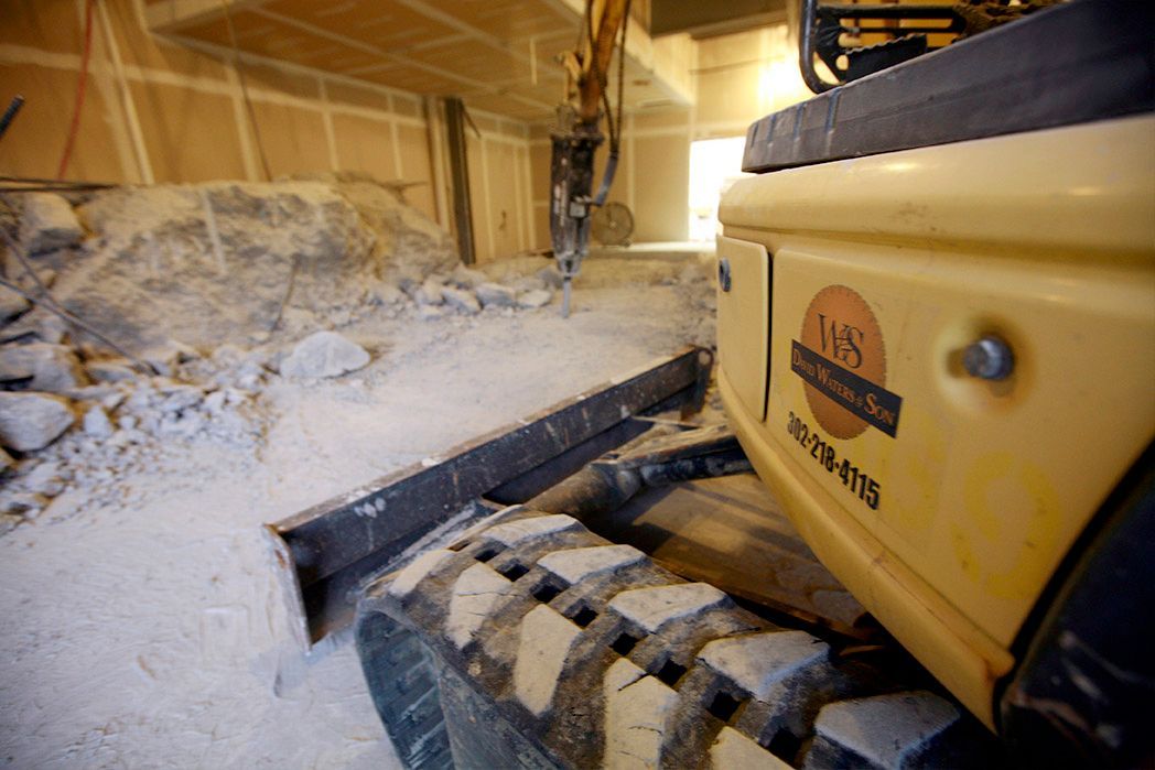 A yellow excavator is being used to demolish a building.