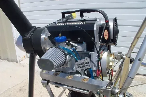 Kawasaki engine with propeller, blue air filter, and cooling fan mounted on a metal frame.