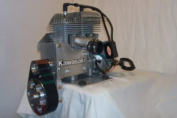 Kawasaki engine with aluminum housing, belt drive, and a spark plug, displayed on a white cloth.