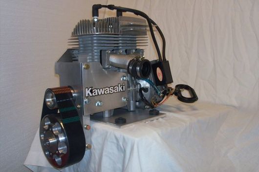 Kawasaki engine, silver with black components, mounted on a base.