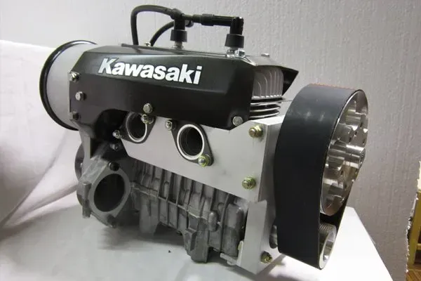 Kawasaki engine, black cover with white lettering, aluminum components, belt drive system, two spark plugs.