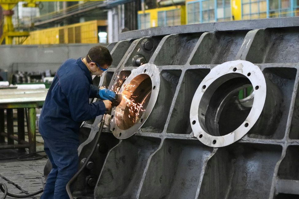 Worker welding a large metal structure in an industrial workshop