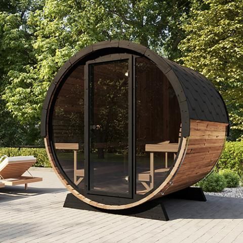 A outdoor wooden barrel sauna with a glass door is sitting on a patio.