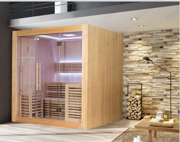 A wooden sauna with glass doors is in a room with a brick wall.