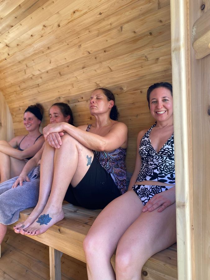 A woman wrapped in a towel is sitting in a wooden sauna.