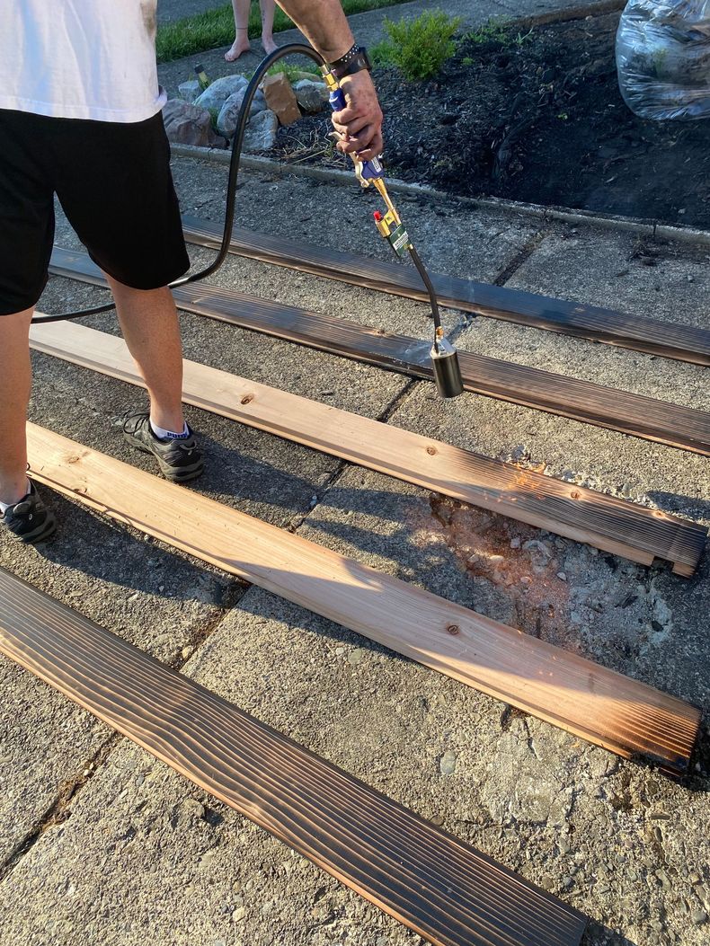 Person hosing down railroad tracks with water spray near a gravel rail bed