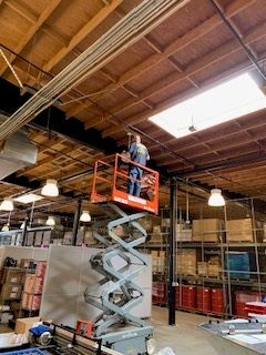 Man is Dtanding on a Scissor Lift - Los Angeles, CA - Gomez Electric Inc