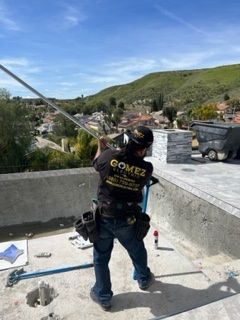 Man is Standing on Top of a Roof Holding a Pole - Los Angeles, CA - Gomez Electric Inc