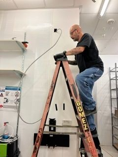 Man is Standing on a Ladder Working on a Wall - Los Angeles, CA - Gomez Electric Inc