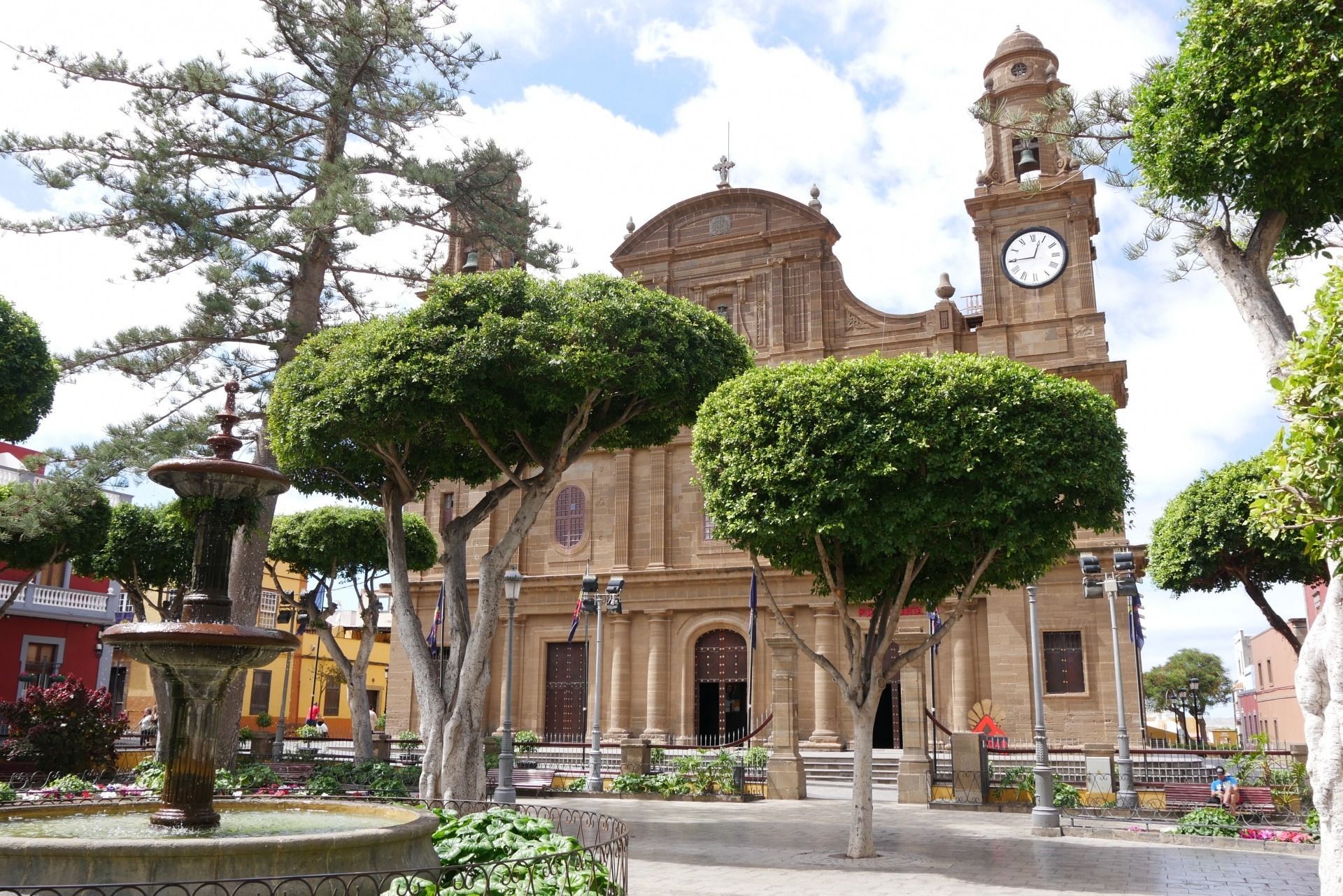 Fachada de una iglesia histórica de piedra con frontón central ornamentado y dos torres contra un cielo nublado.