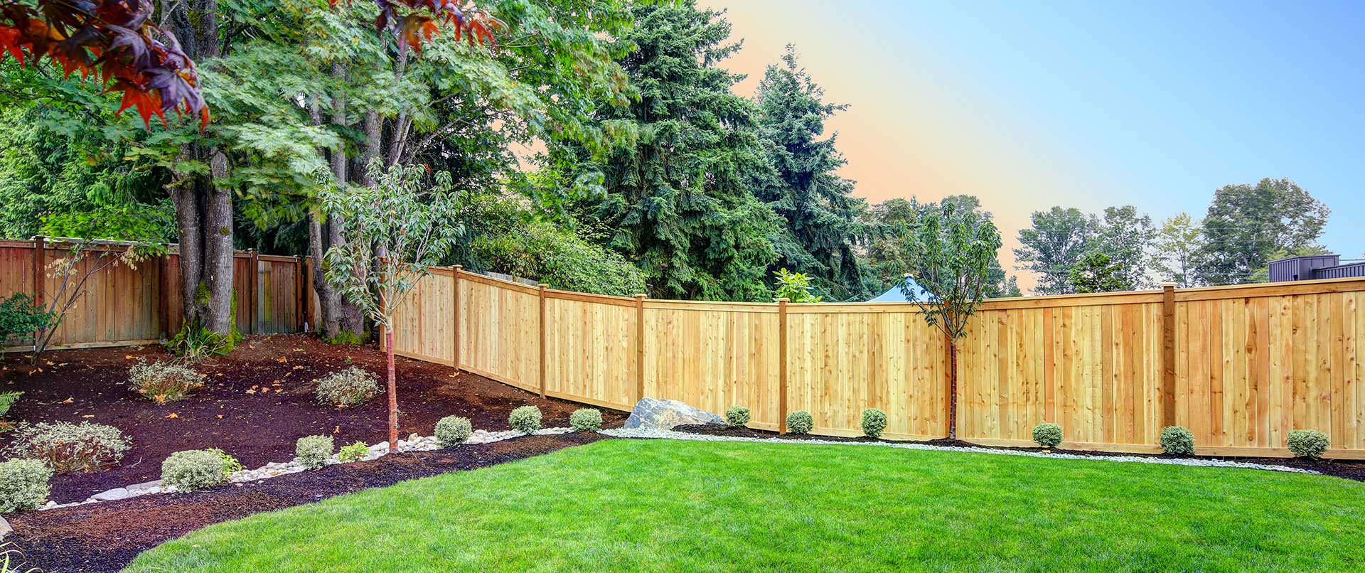 View of an attractive backyard with new planting beds and well kept lawn.