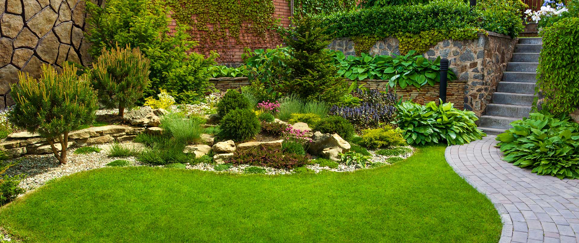 Garden stone path with grass growing up between the stones.Detail of a botanical garden.