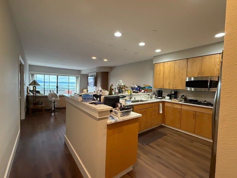 A kitchen with wooden cabinets , stainless steel appliances , and a large island.