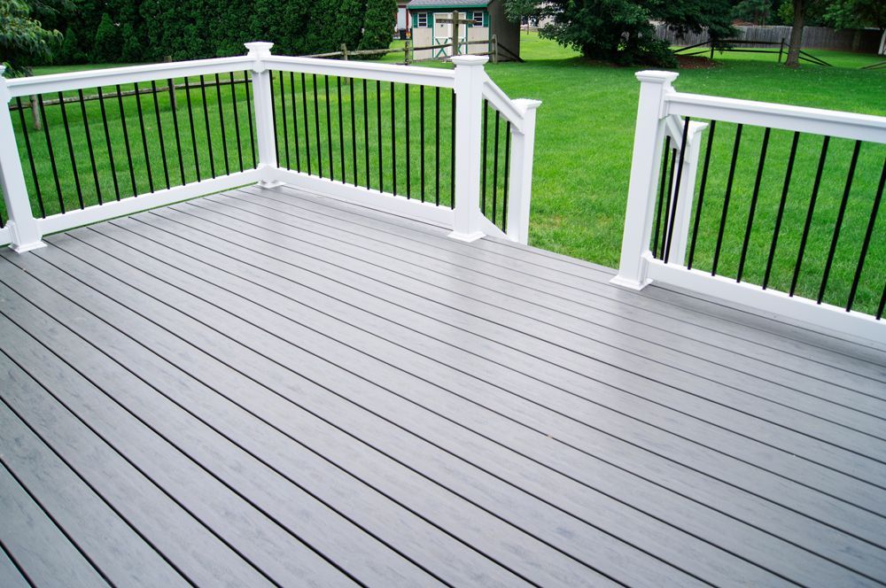 a deck with a white railing and a green shed in the background