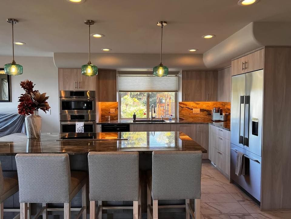 Modern kitchen with an island, pendant lights, stainless steel appliances, and wood cabinetry.