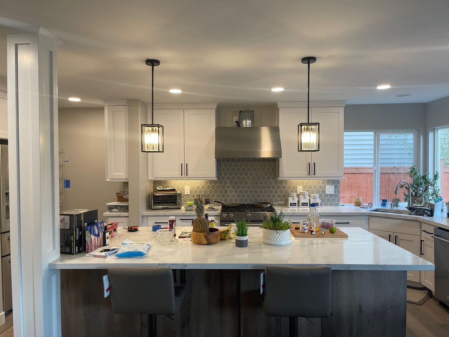 A kitchen with white cabinets , stainless steel appliances , and a large island.