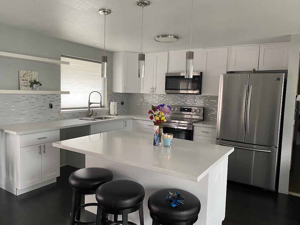 A kitchen with white cabinets , stainless steel appliances and a large island.