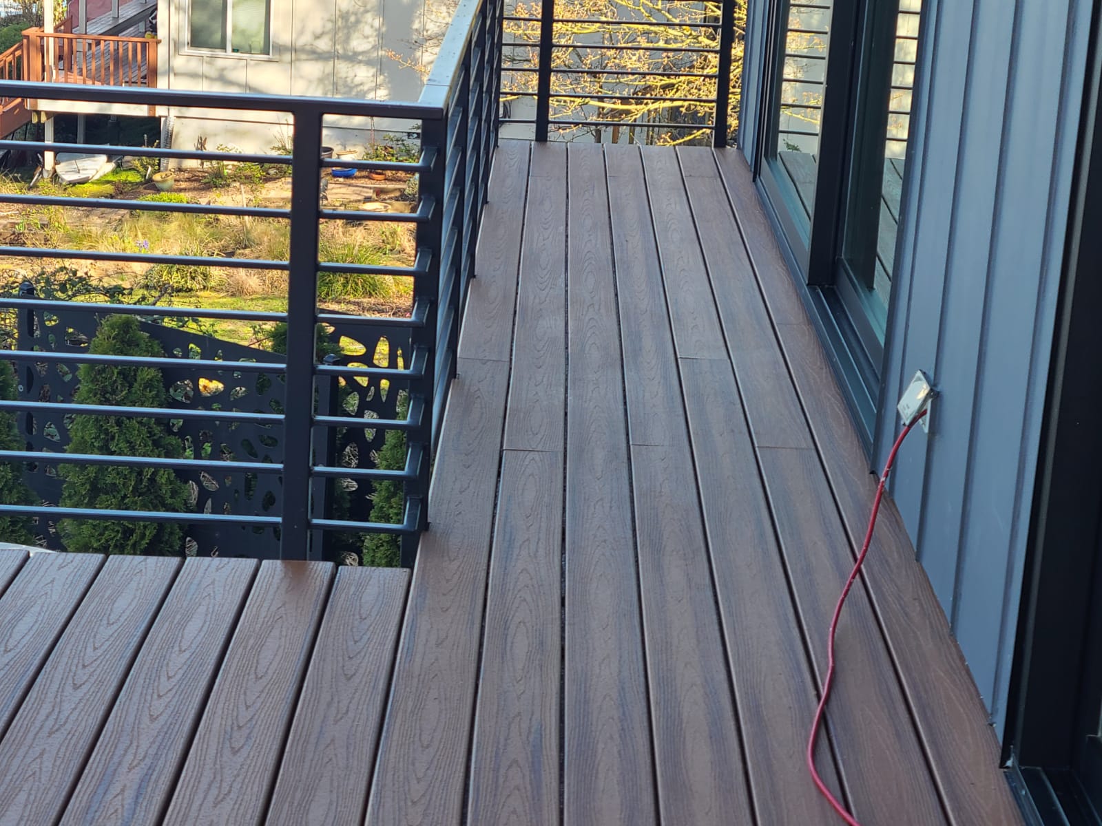 A wooden deck with a metal railing and sliding glass doors