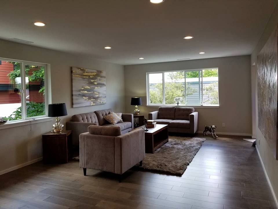 Living room with neutral tones, two sofas, a chair, and a rug on wood flooring.
