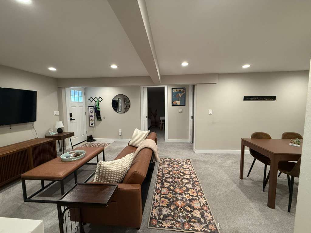 Living room with a couch, table, rug, TV, and dining area. Neutral colors.