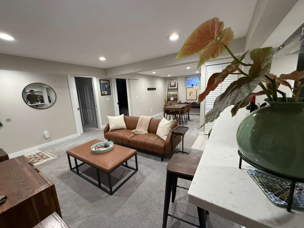Living room with a brown leather couch, coffee table, and large potted plant.