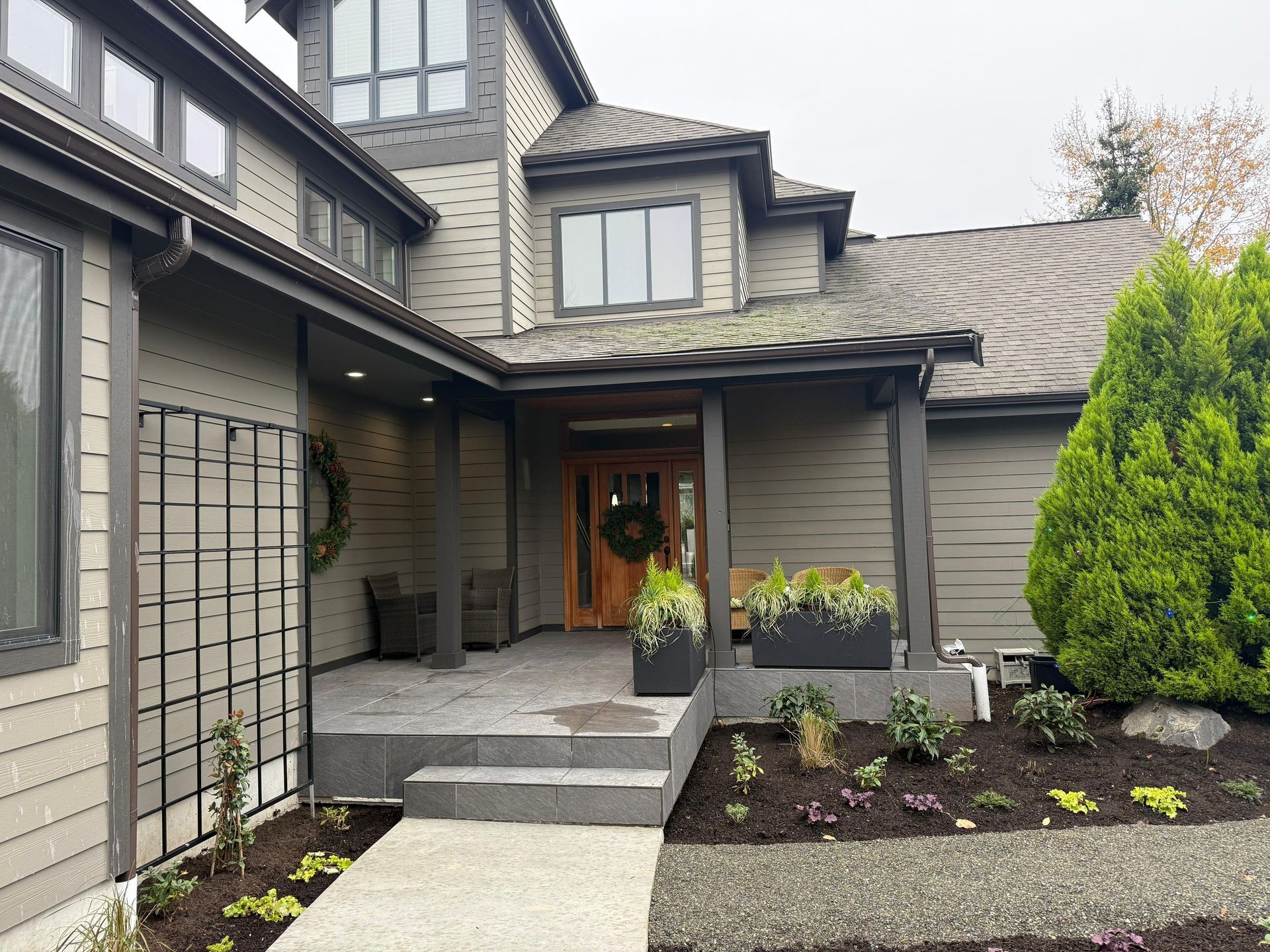 Modern house exterior with covered entry, landscaping, and dark trim.