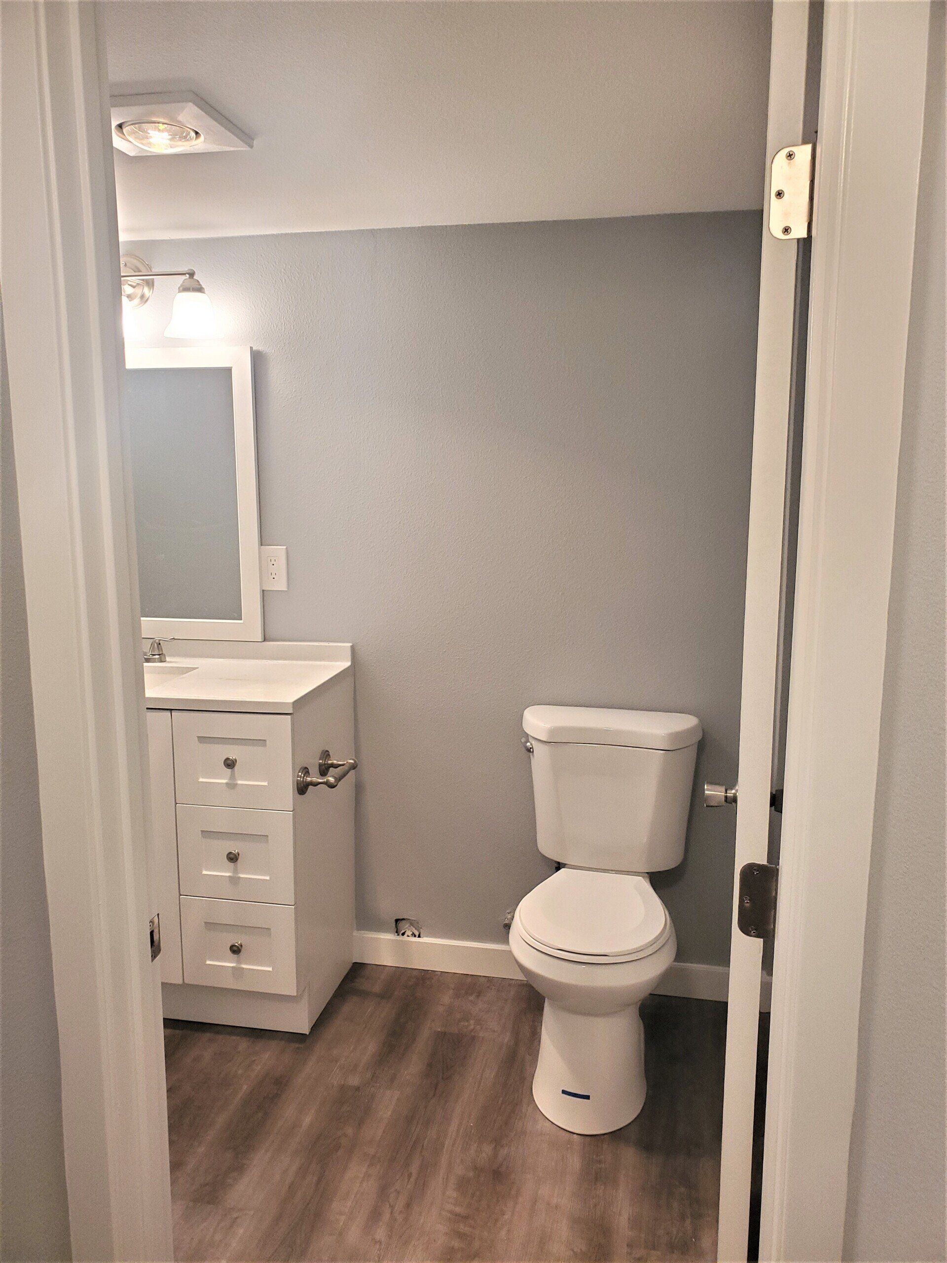 A bathroom with a toilet , sink and mirror