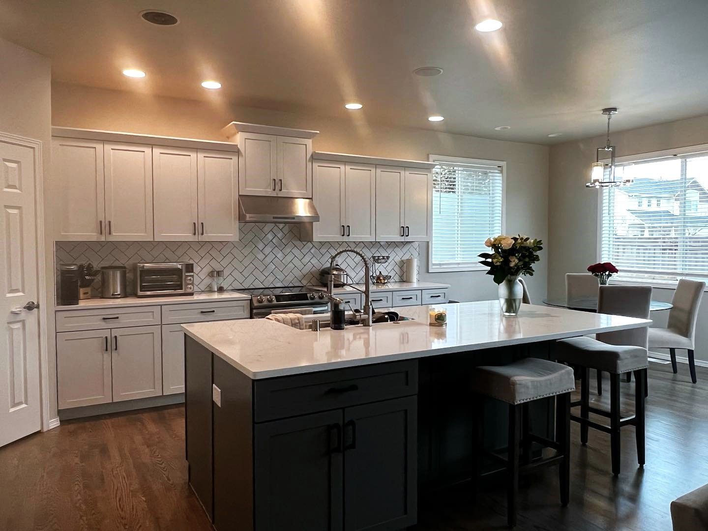 Modern kitchen with white and gray cabinets, island, and dining area.