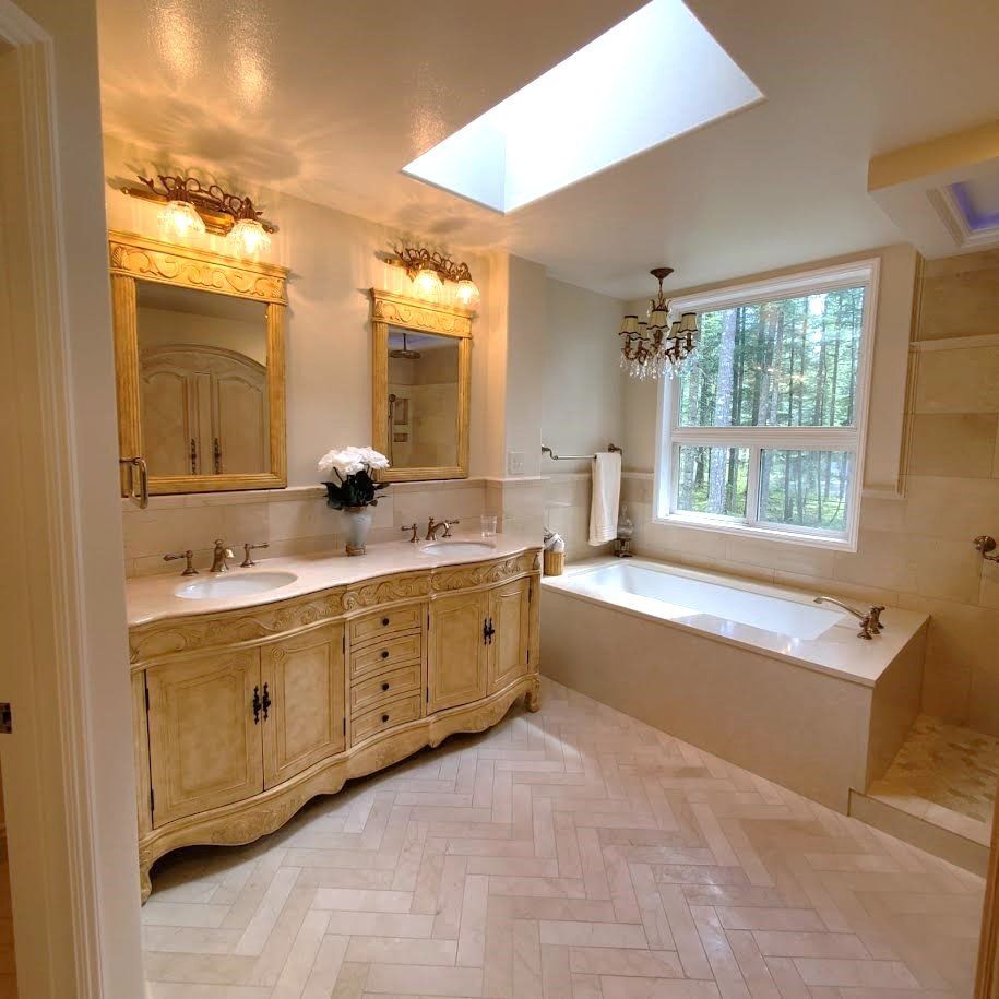 A bathroom with two sinks , a tub and a skylight