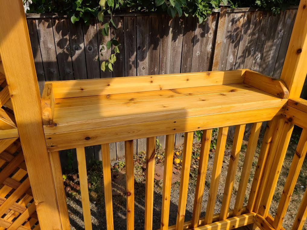 A wooden bench is sitting on top of a wooden railing.