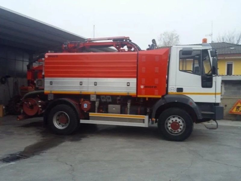 Un camioncino rosso e bianco parcheggiato sotto una tettoia. Ha una gru sul retro.