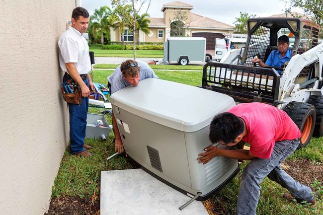 A group of men are working on a generator outside of a house.