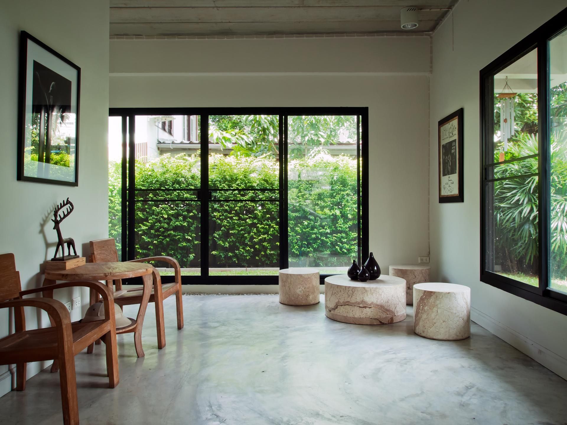 A living room with a lot of windows and tables and chairs.