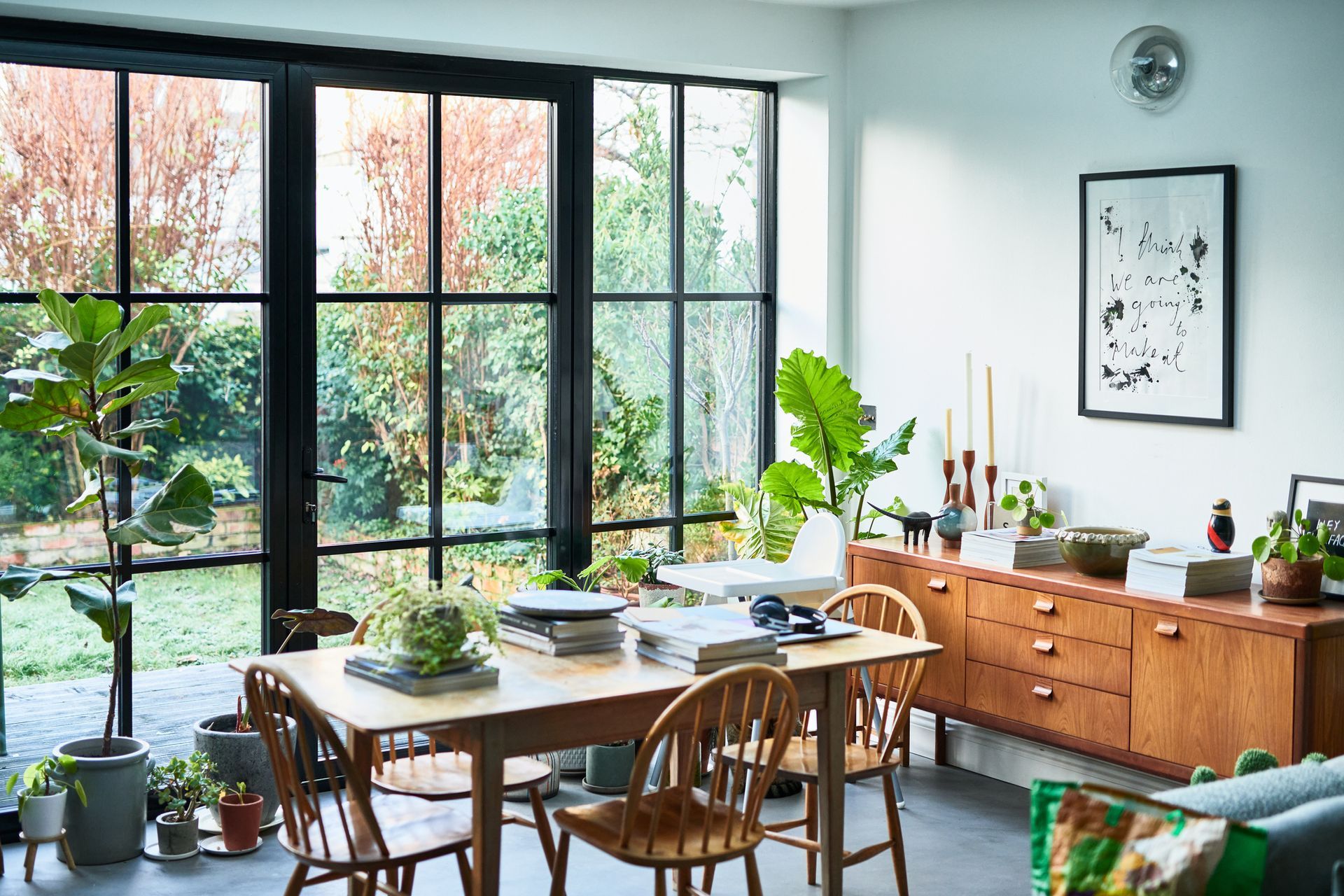Modern lounge with dining table by large window set up as home office for window contractors.