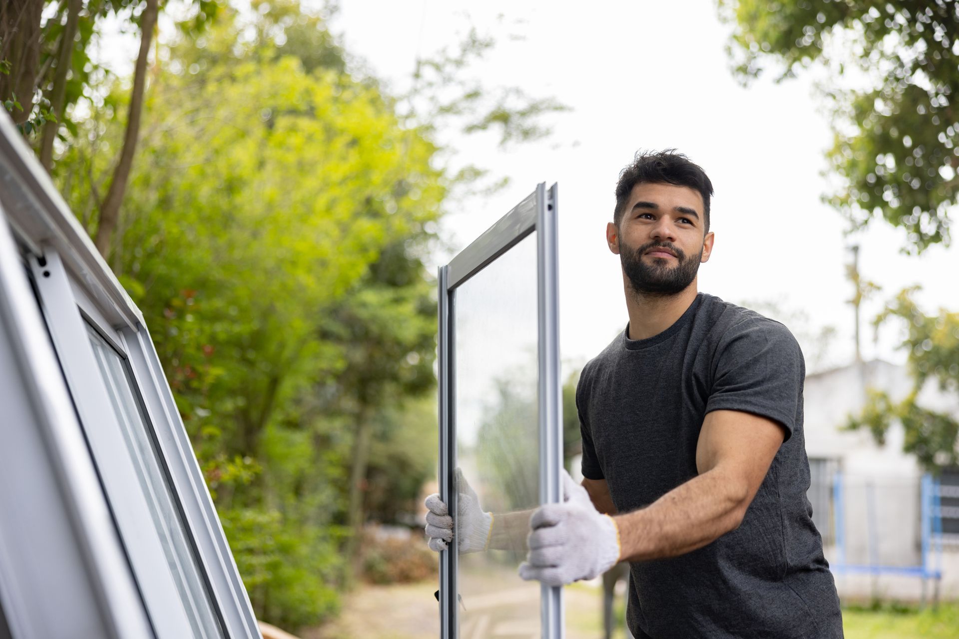 Person holding window frame outdoors with gloves.
