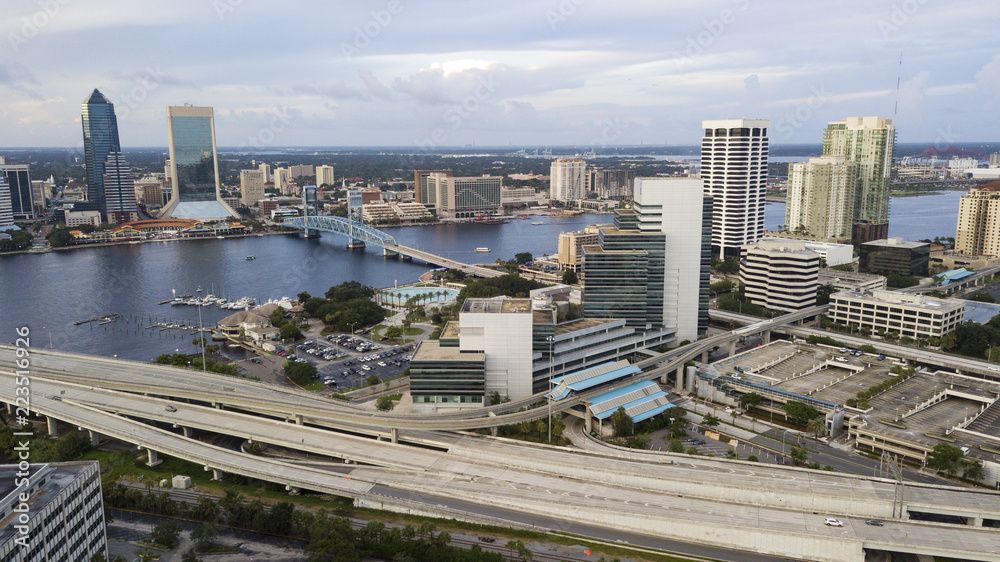Photo of a riverside area, showing various buildings, and a ship on the water, preparing to go under a bridge
