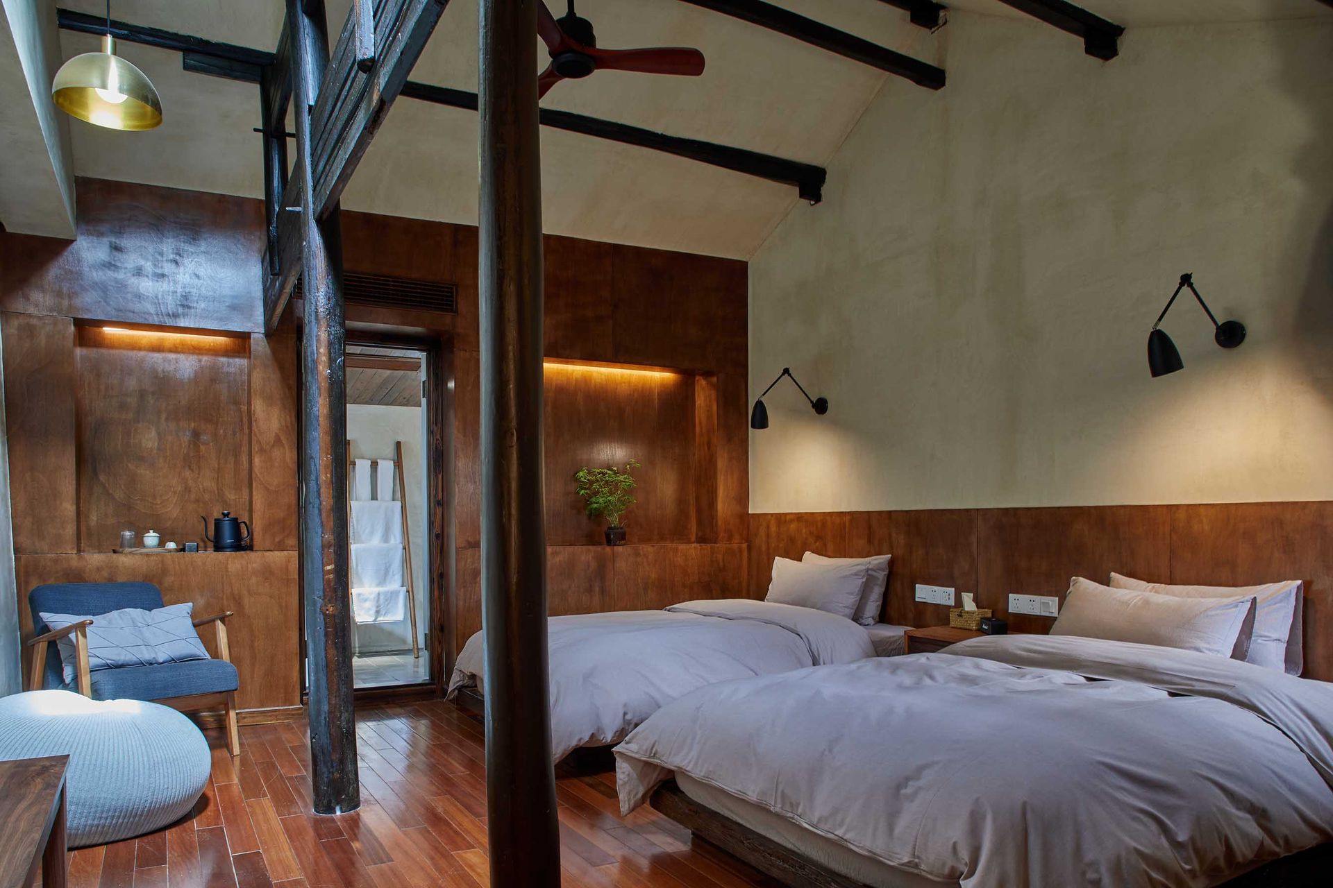 Rustic bedroom with wood beams, twin beds, and warm wall lighting