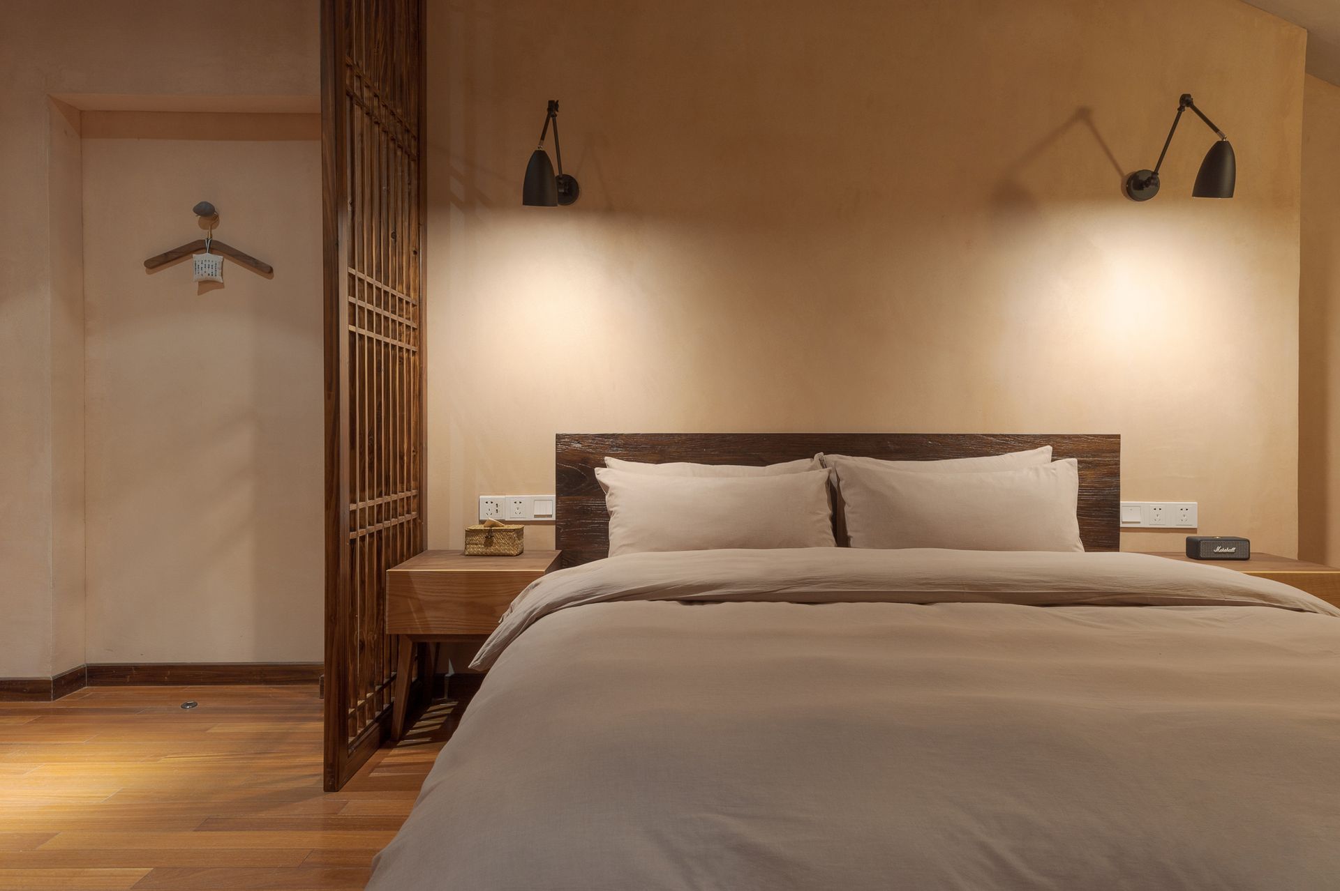 Modern bedroom with a large bed, warm wood walls, pendant lights, and a sliding door on the left