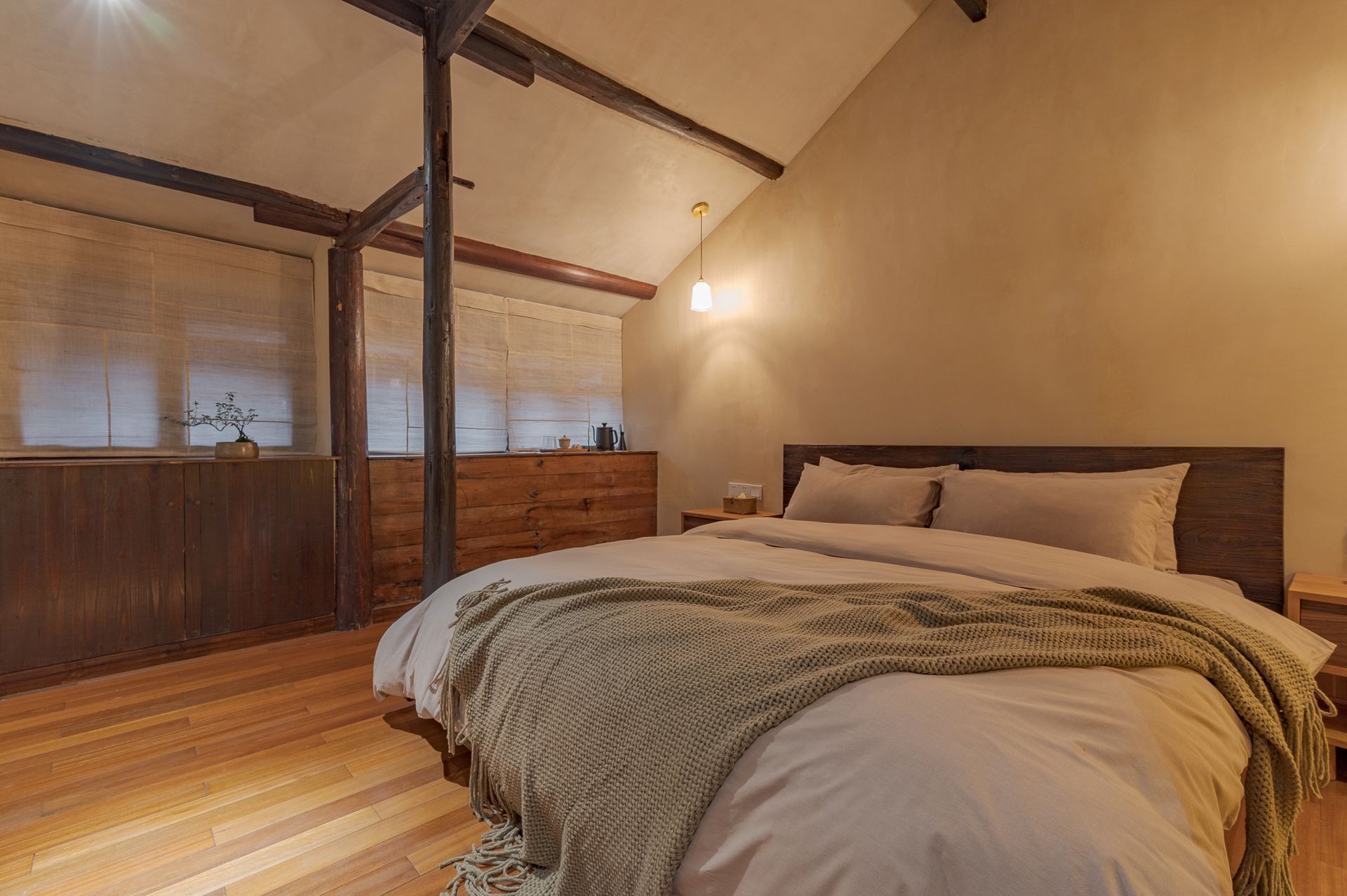 Cozy bedroom with a king bed, wood-paneled walls, and sloped ceiling in warm lighting