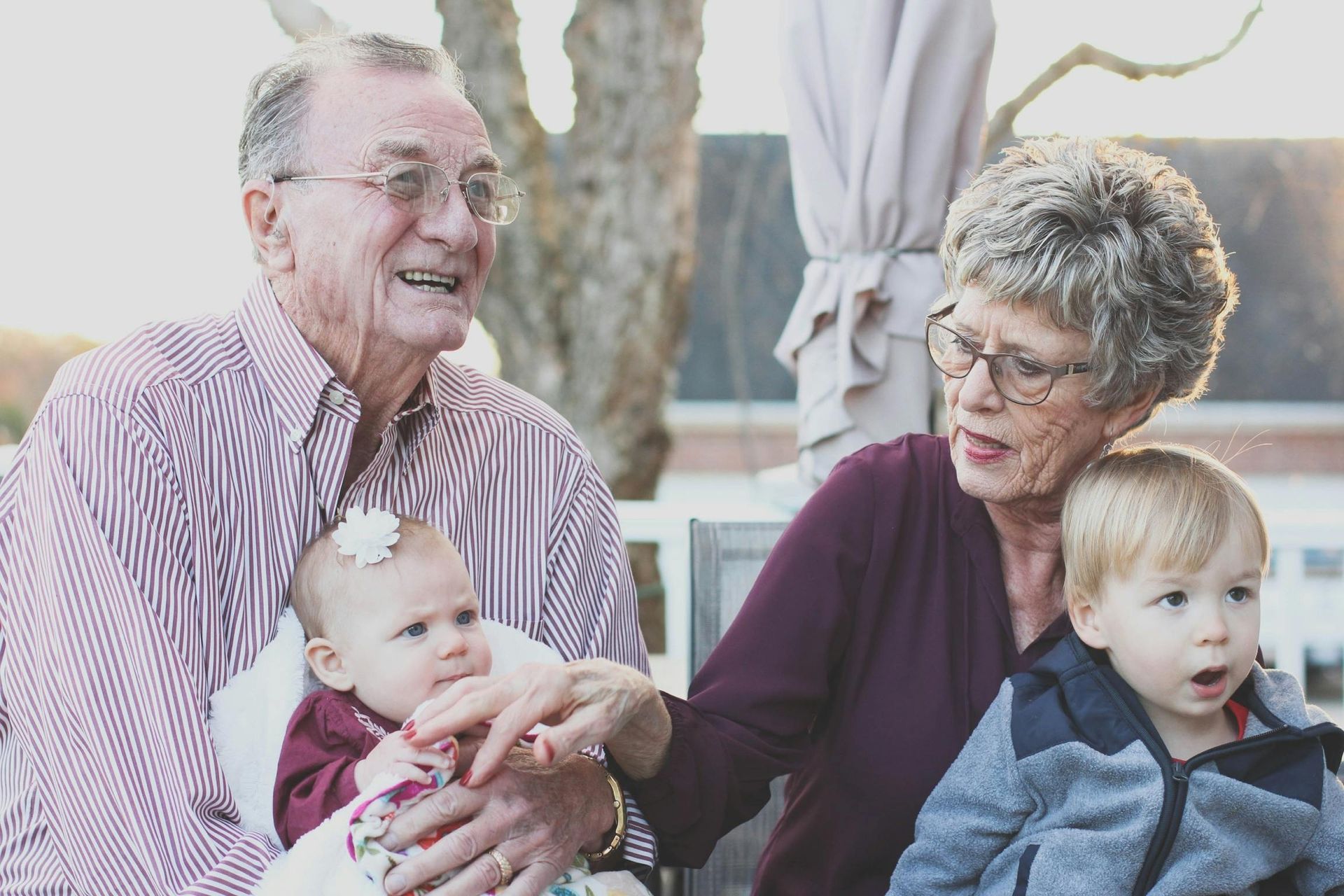 An elderly couple is holding a baby and two young children.