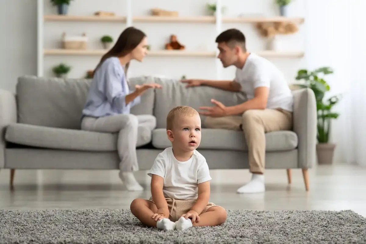 Il bambino è seduto sul tappeto, i genitori litigano sul divano in soggiorno.