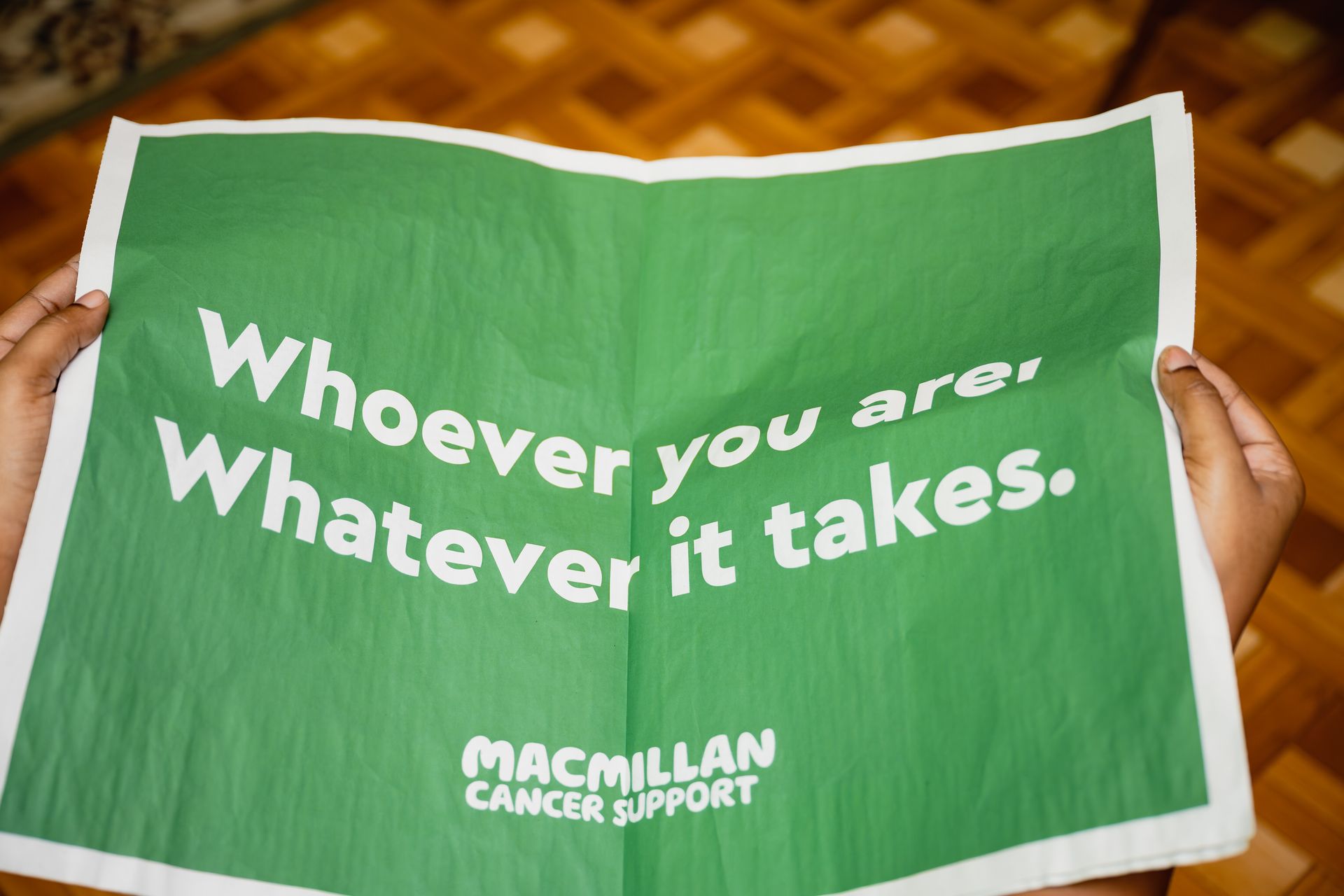 Hands hold a green sign that reads, 