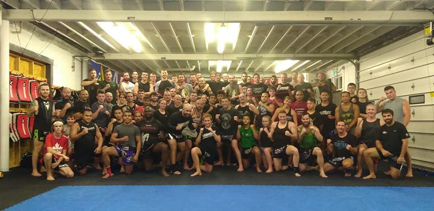 A large group of people in a gym, many in athletic gear, posing for a photo.
