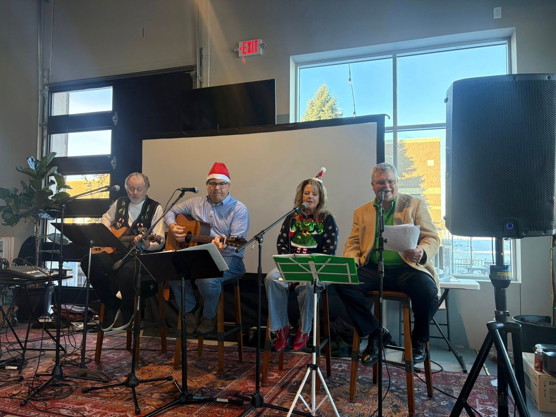 Four people performing music indoors with holiday attire.