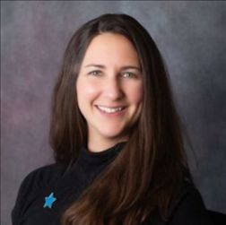 Rotary Club meeting; people seated at tables, speaker at podium showing a slide, American flag in background.