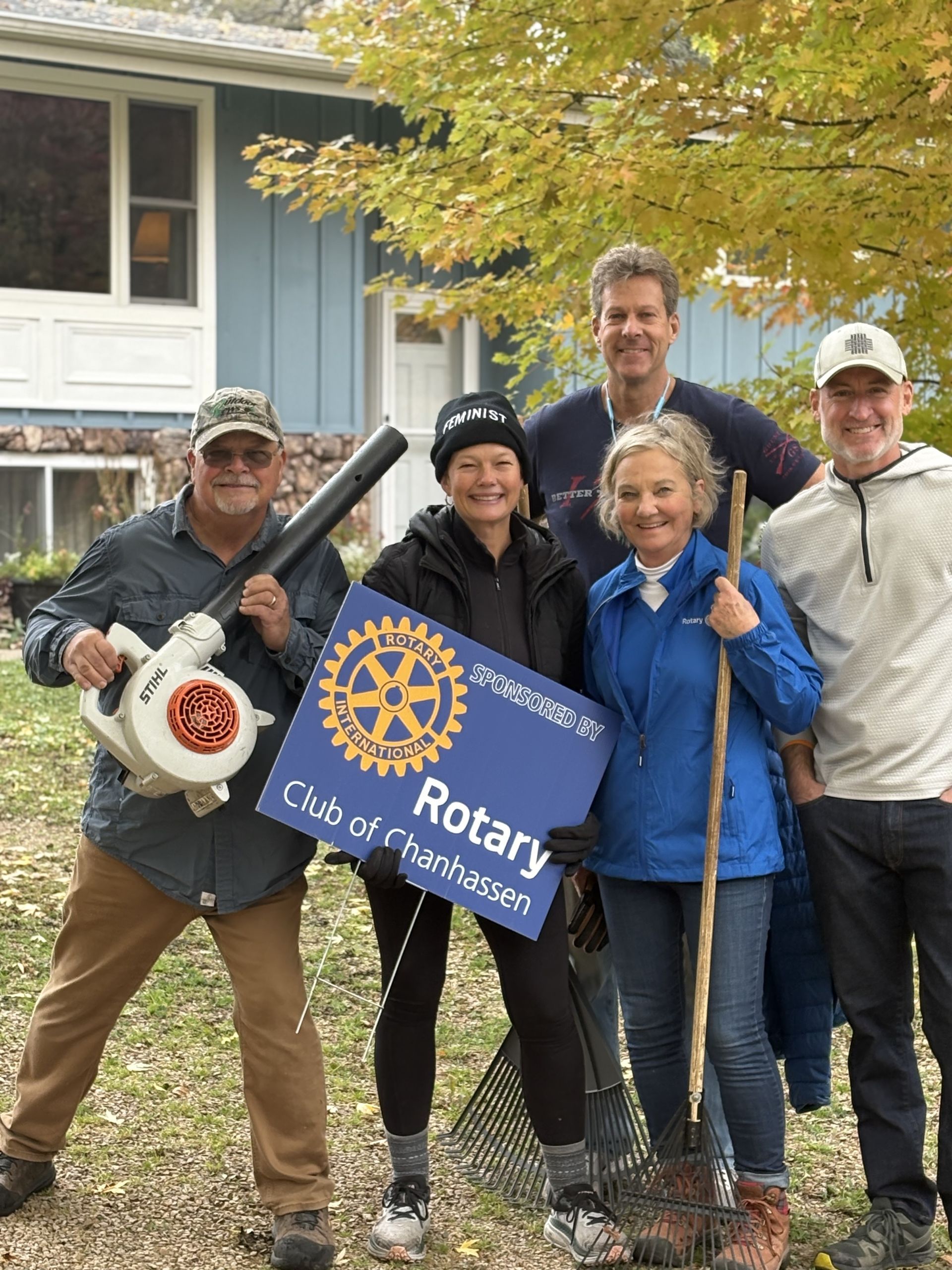 Volunteers from the Rotary Club of Charlevoix, holding tools, cleaning up outdoors.