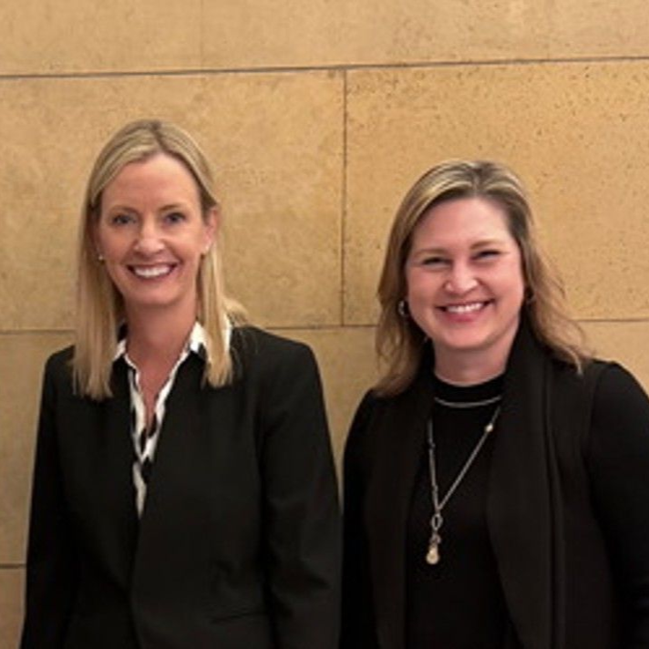 Rotary Club meeting; people seated at tables, speaker at podium showing a slide, American flag in background.