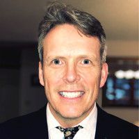Rotary Club meeting; people seated at tables, speaker at podium showing a slide, American flag in background.
